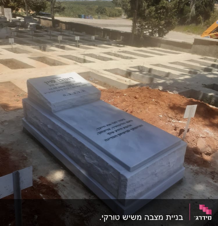 מצבה לבנה עם כיתוב בעברית בבית קברות